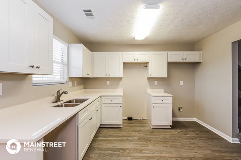 a kitchen with white cabinets and a sink and a window