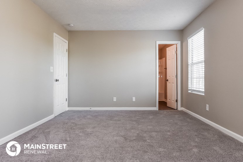 the spacious living room with carpeting and a door to the hallway