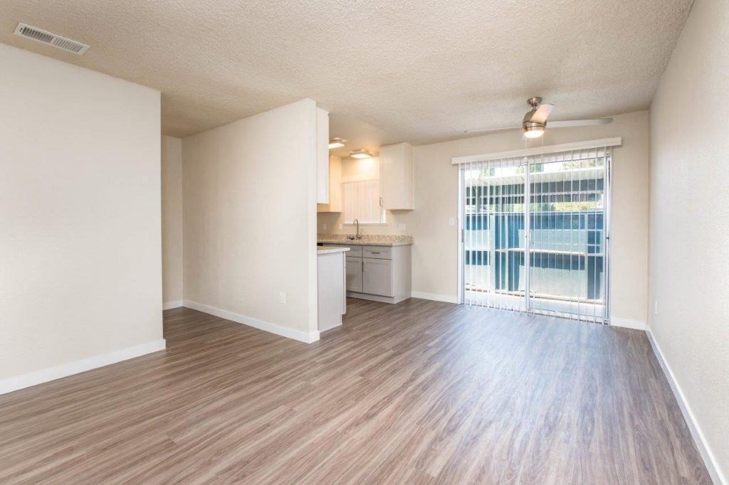 an empty living room and kitchen with a sliding glass door