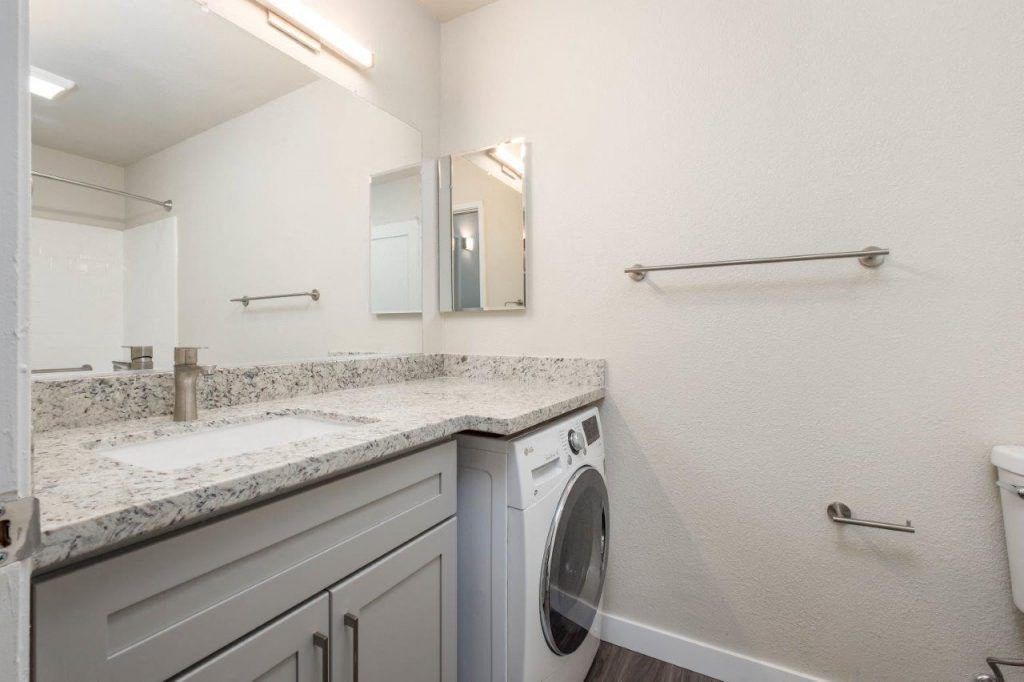 a white laundry room with a sink and a washing machine