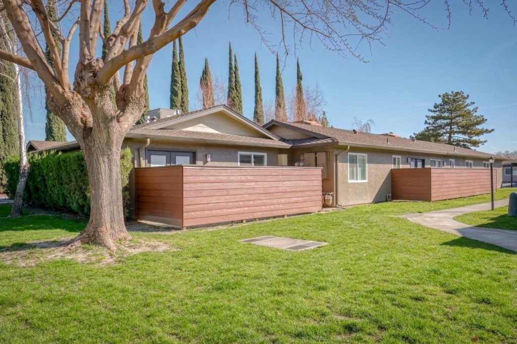 the front of a house with a yard and a tree