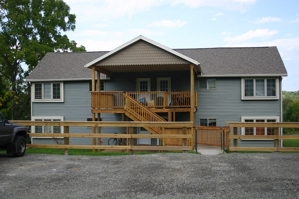 a house with a deck and a fence in front of it
