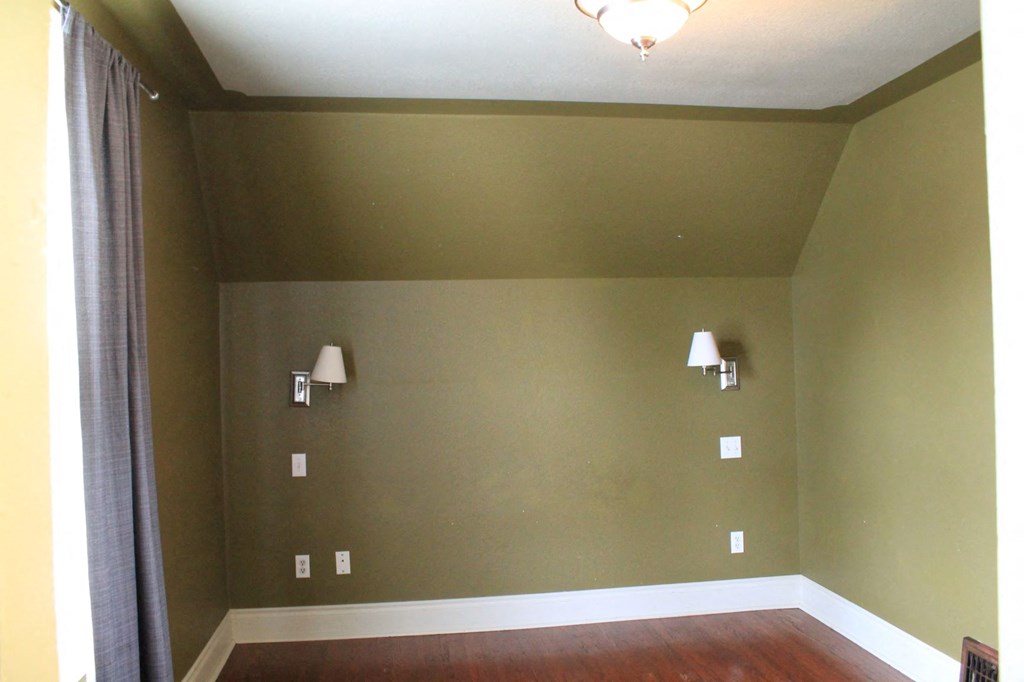 an empty room with green walls and white lamps