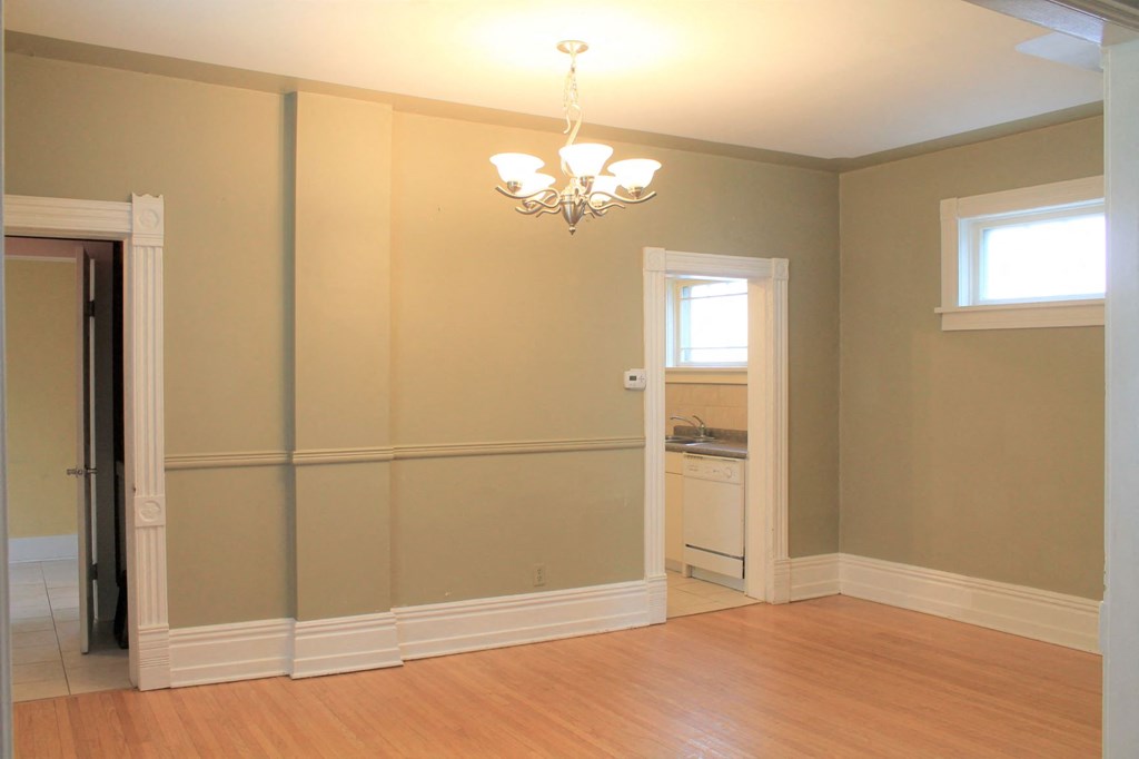 a empty room with a door to a bathroom and a chandelier