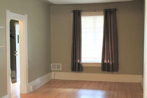 a living room with a window and curtains and a wooden floor