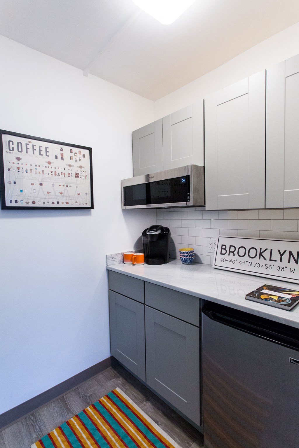 a small kitchen with white cabinets and a counter top and a microwave