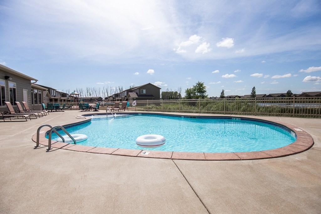 a resort style pool with lounge chairs around it and a building in the background
