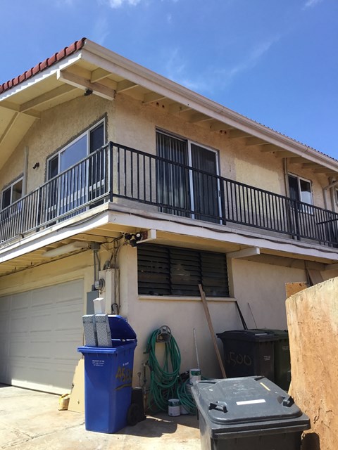 a house being remodeled with trash cans in front of it