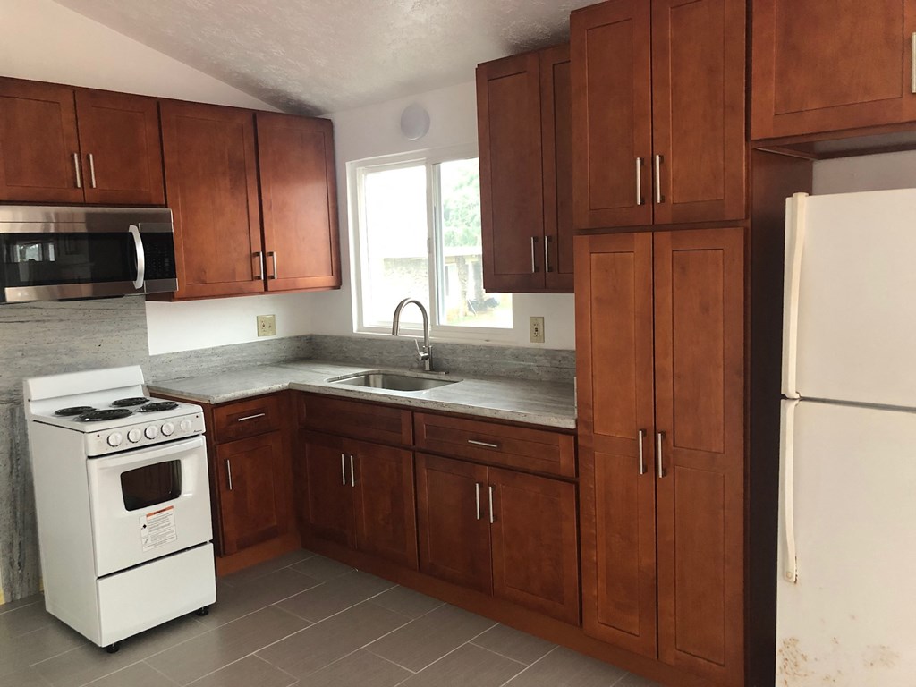 an empty kitchen with wooden cabinets and white appliances