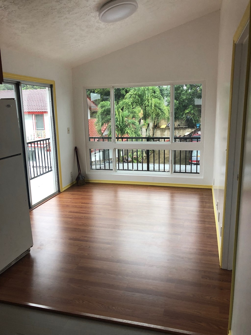 an empty living room with wooden floors and a large window