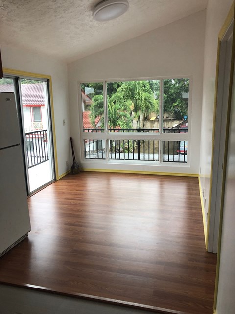 an empty living room with wooden floors and a large window
