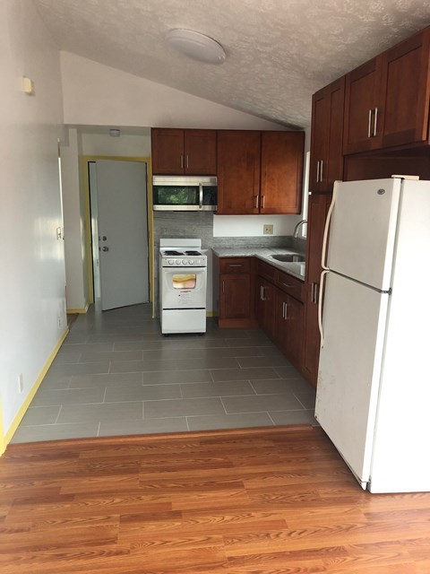 an empty kitchen with wooden floors and white appliances