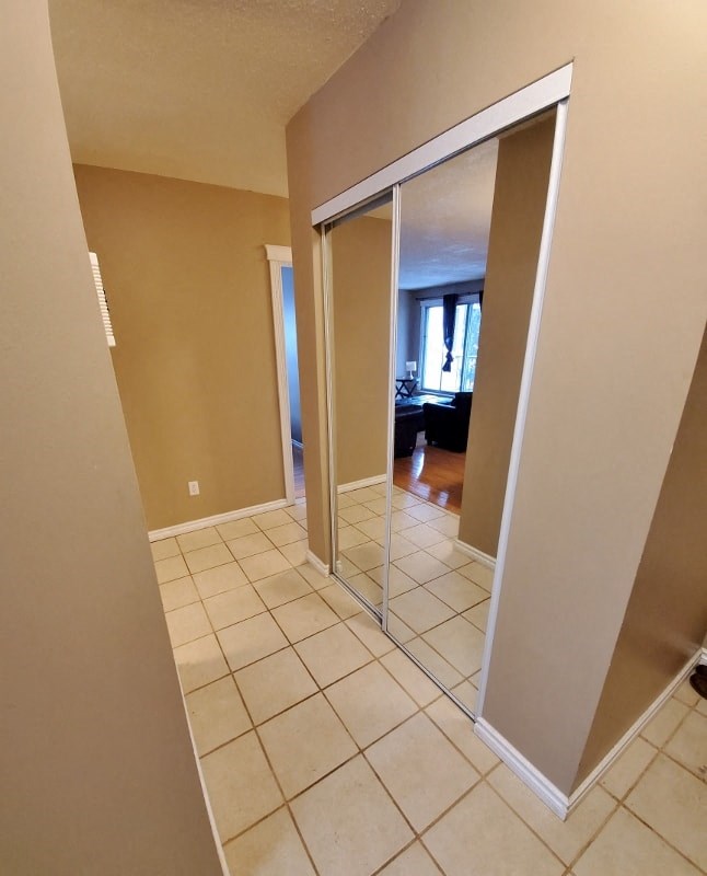 a bathroom with a mirrored closet door and a tiled floor