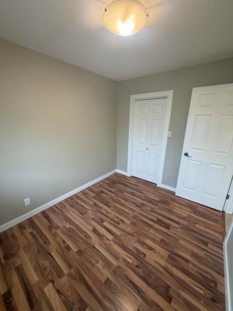 A room with wooden flooring and two white doors.