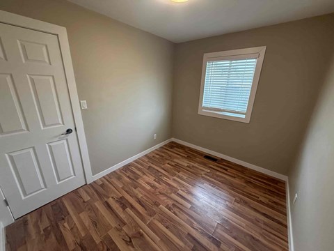 A room with a white door and a window with blinds.