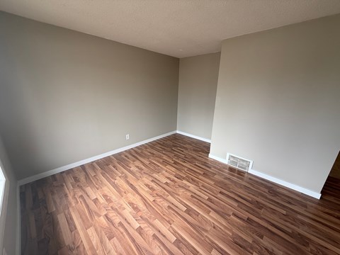 A room with wooden flooring and white walls.