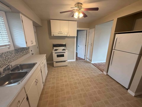 A kitchen with a tile floor and a ceiling fan.