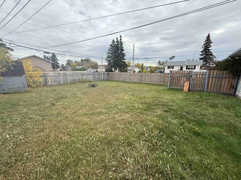 A backyard with a wooden fence and a picnic table.