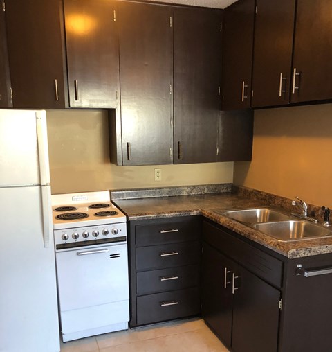 an empty kitchen with white appliances and black cabinets