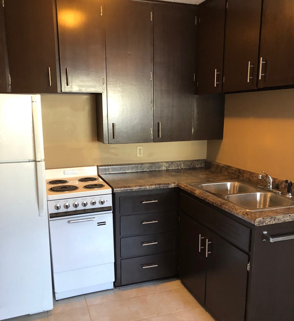 an empty kitchen with white appliances and brown cabinets