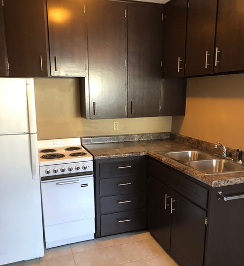 an empty kitchen with white appliances and brown cabinets