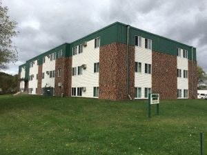 an apartment building on top of a green hill