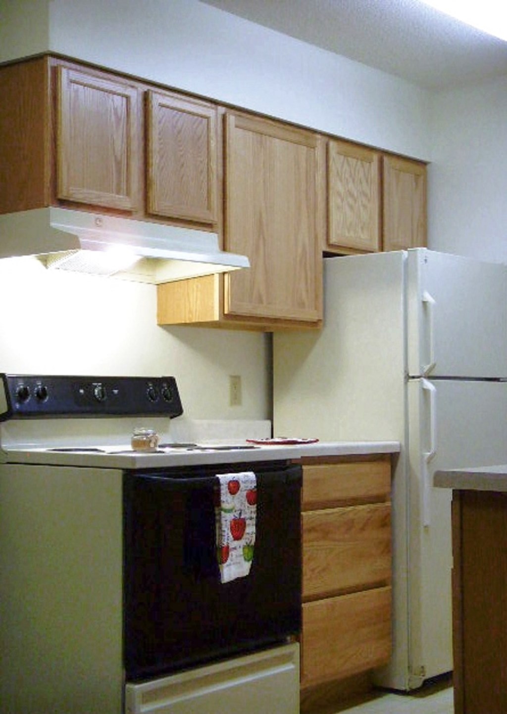 A kitchen with a black stove top oven and a white refrigerator.