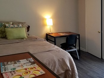 furnished bedroom with desk, bed, and dresser