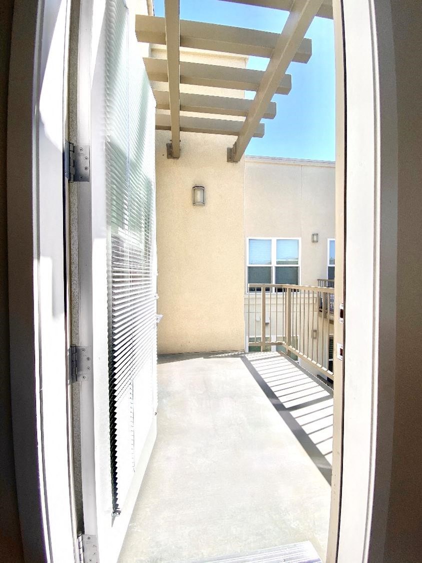 a view of the balcony from the open door of a condo