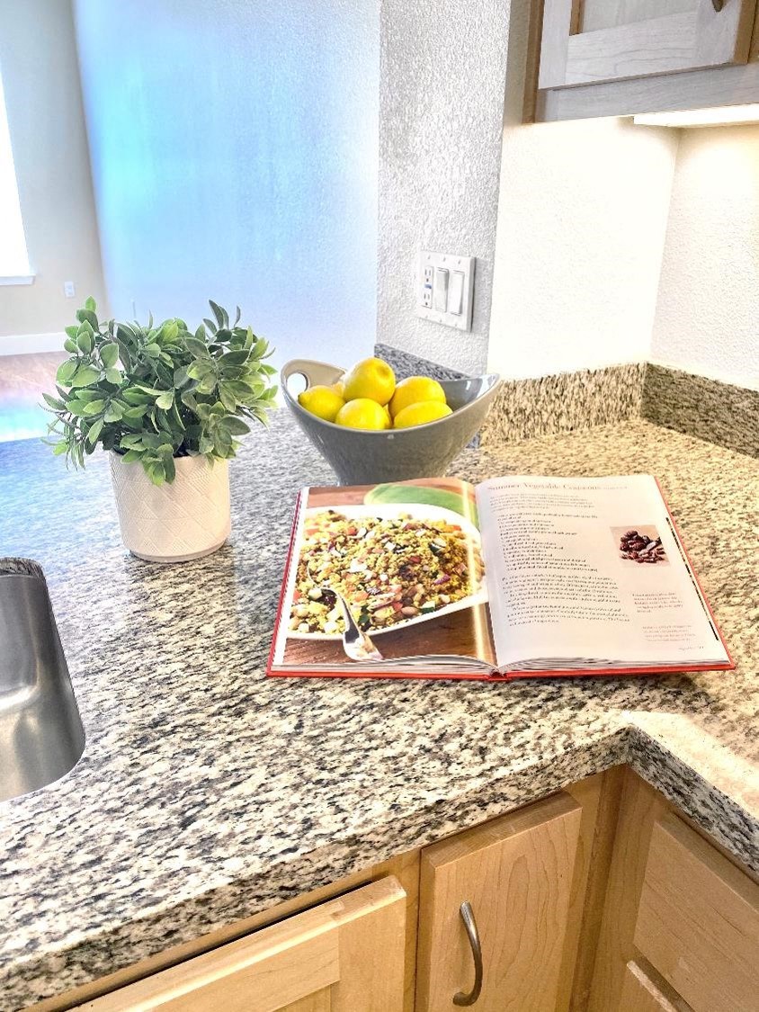 a kitchen counter with a book and a bowl of lemons on it