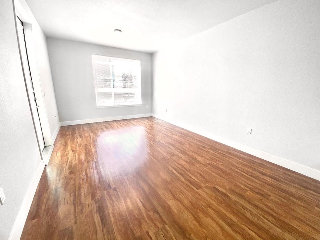 an empty room with wood floors and a window