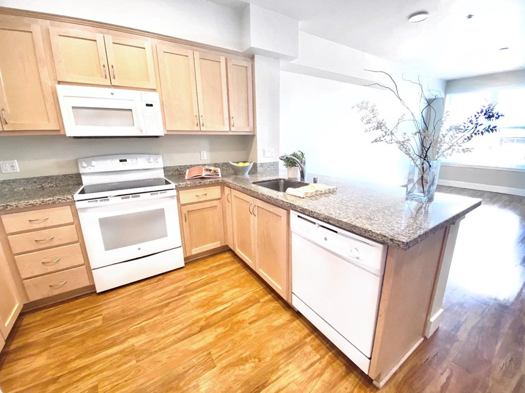 a kitchen with white appliances and wooden floors