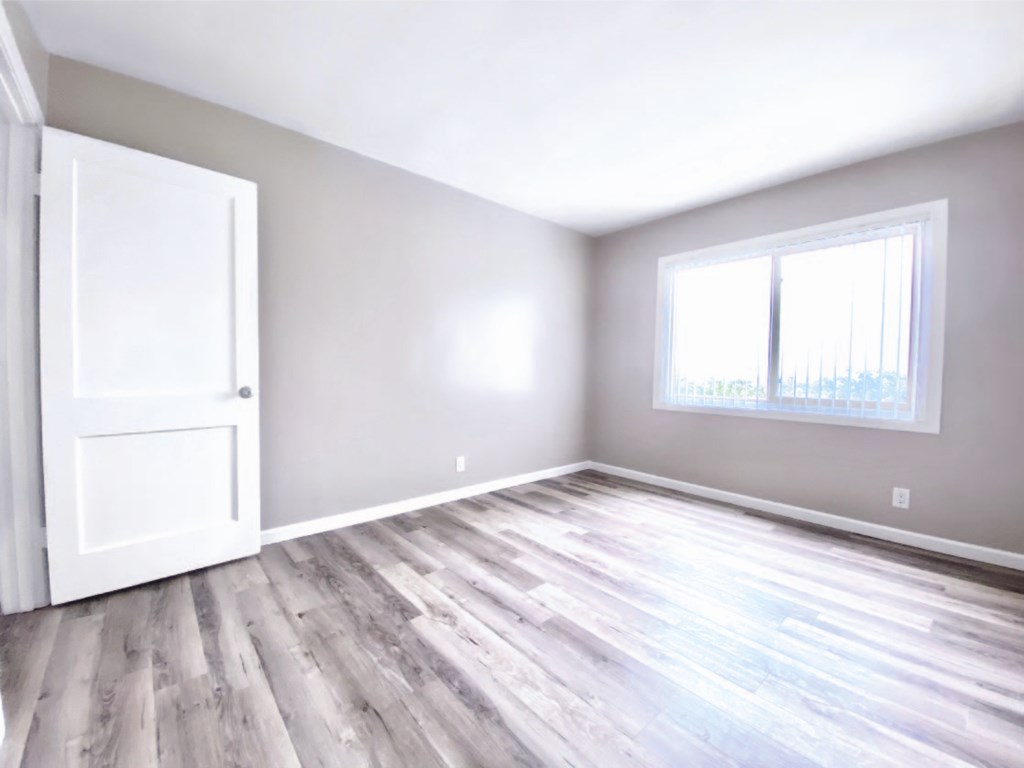 an empty room with wood floors and a door and window