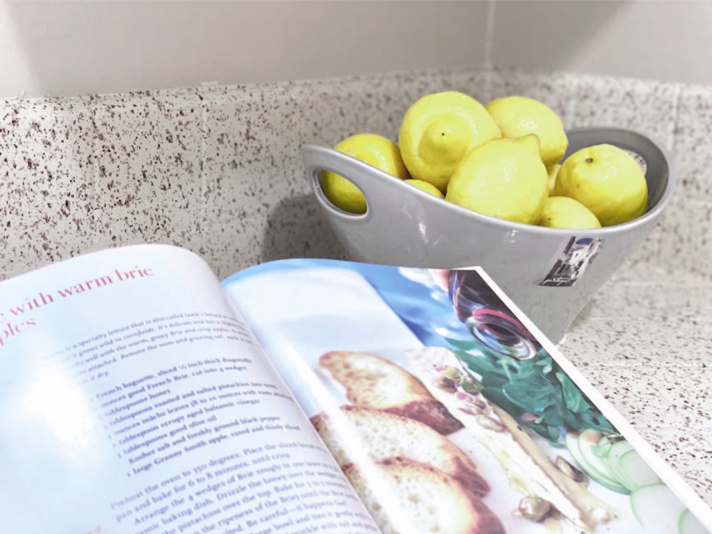 a book and a bowl of lemons on a counter