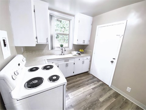 a kitchen with white cabinets and a stove and a window