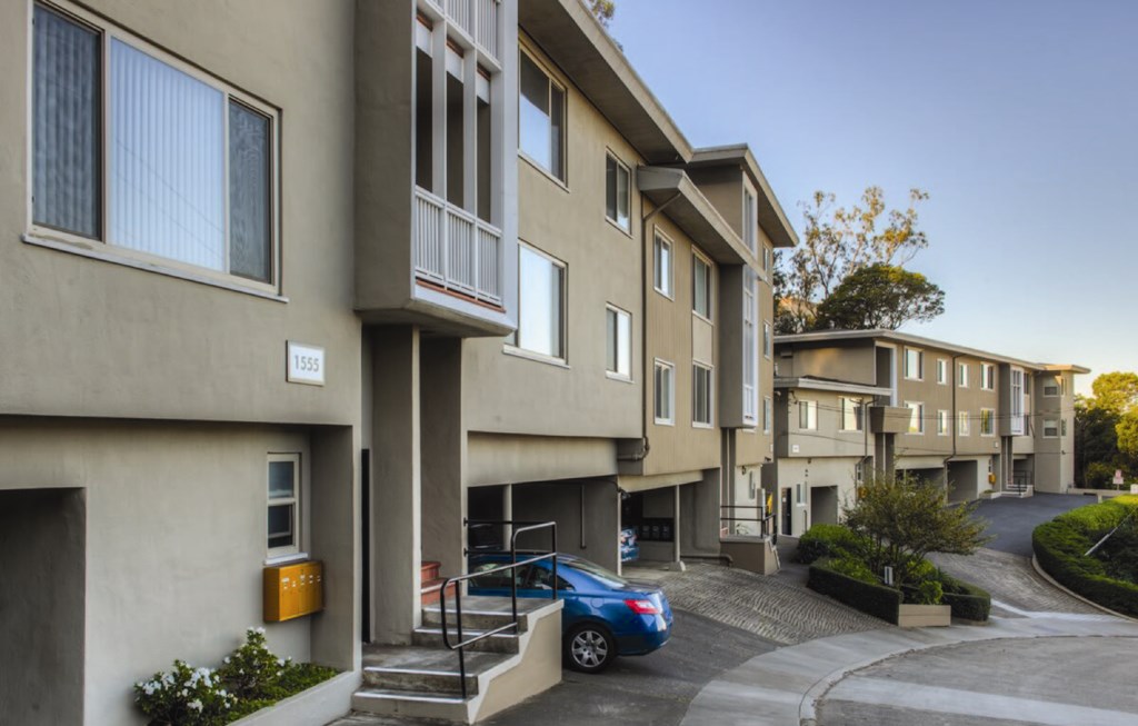 a row of apartments with a blue car parked in front