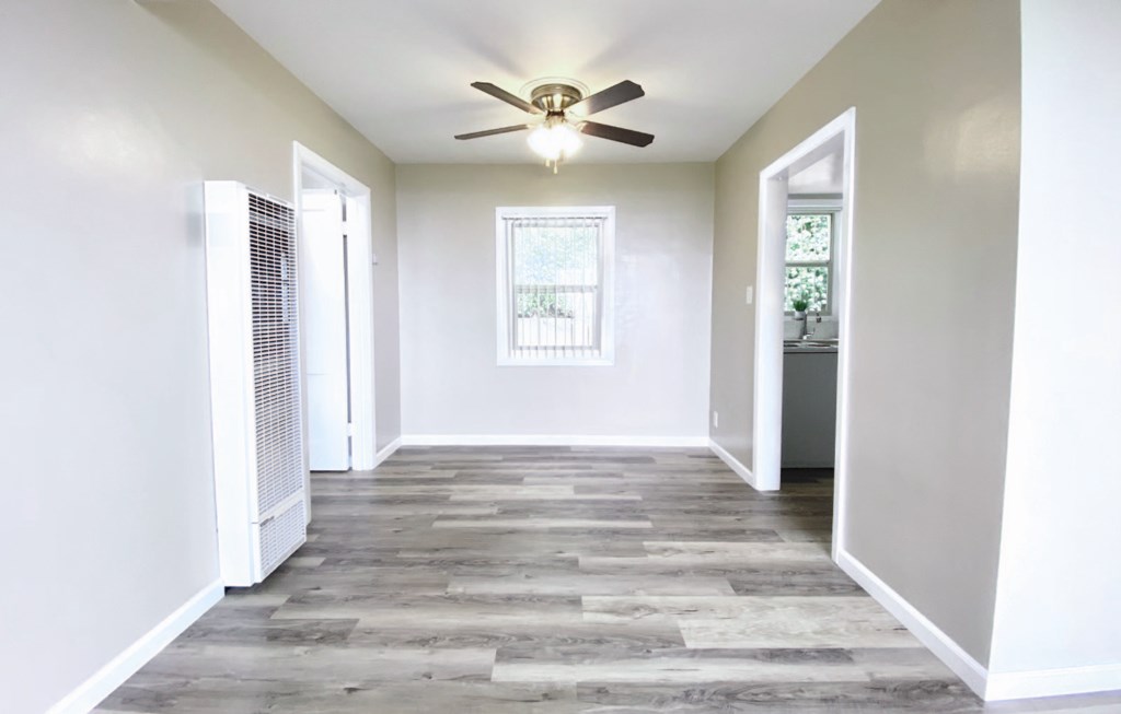 an empty living room with a ceiling fan and white walls