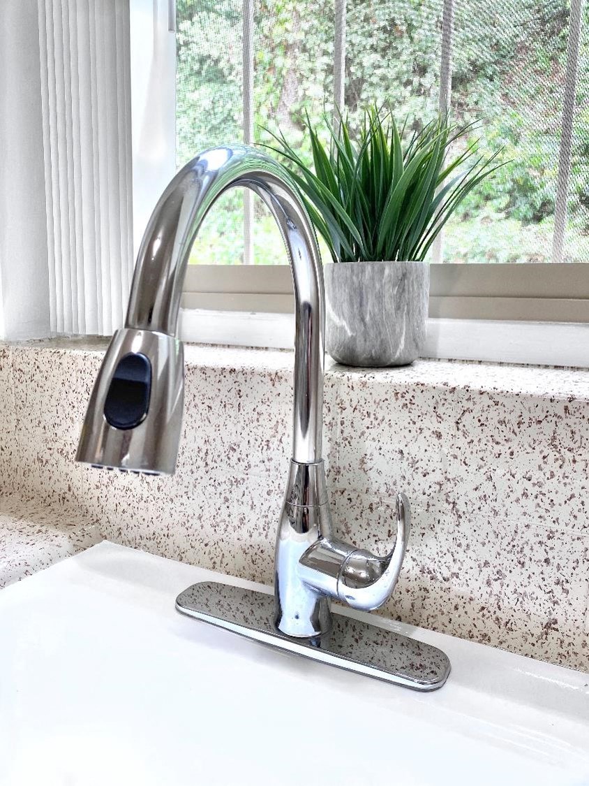 a kitchen sink with a chrome faucet in front of a window