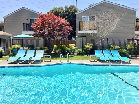 a swimming pool with chairs and a house in the background