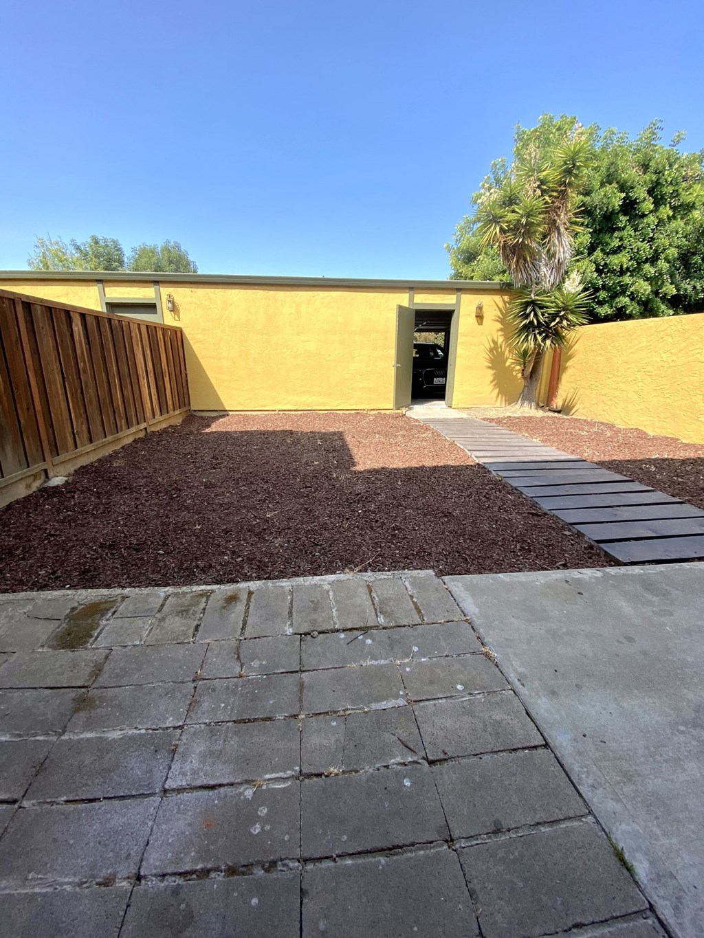 a backyard with a wooden fence and a stone walkway