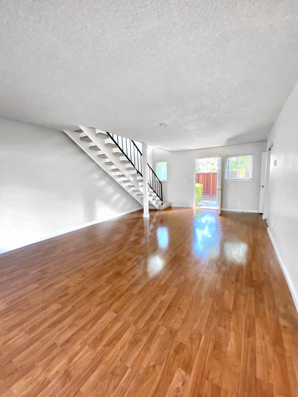 an empty living room with a hard wood floor and a staircase