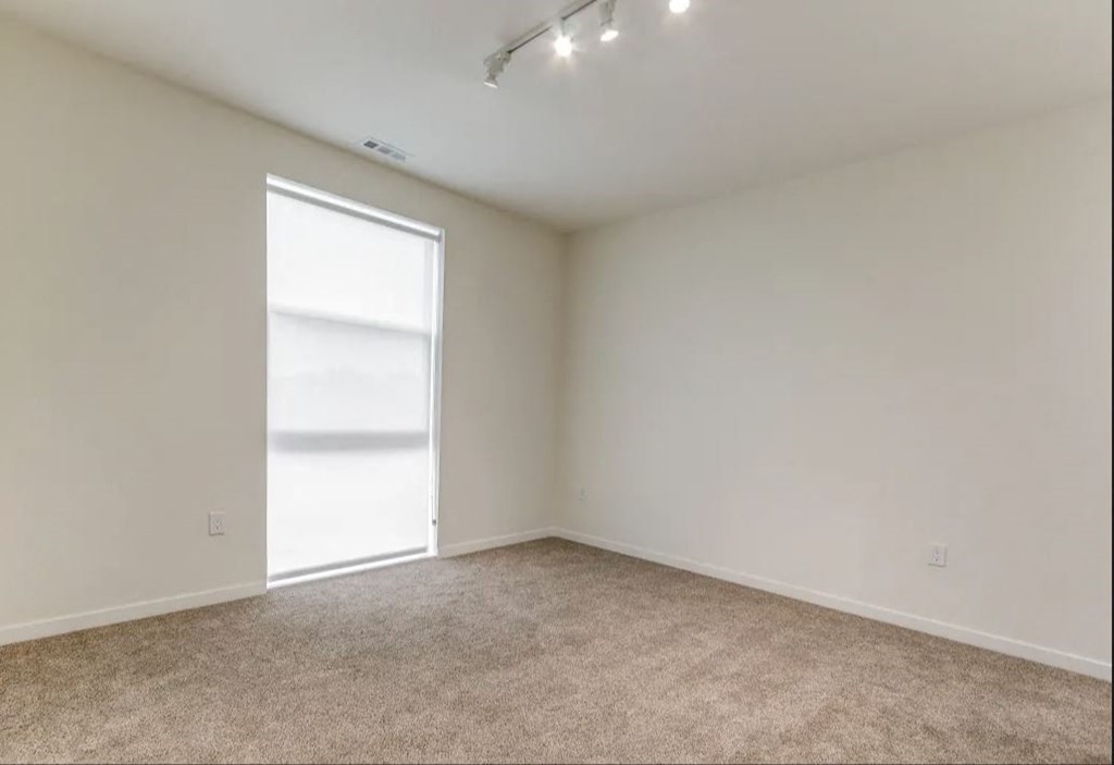 an empty living room with a window and carpet