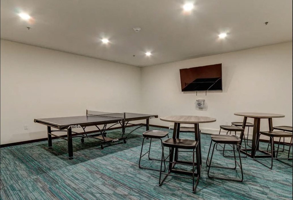a game room with tables and chairs and a television