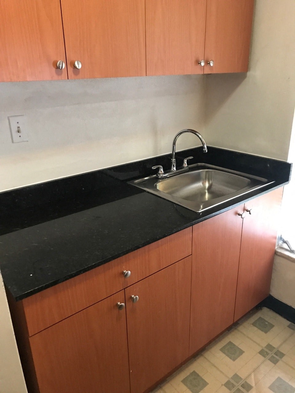 an empty kitchen with a sink and wooden cabinets