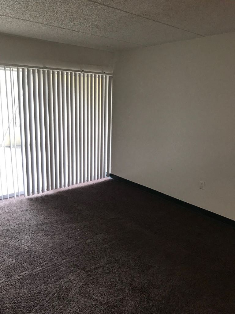 an empty living room with blinds on the window