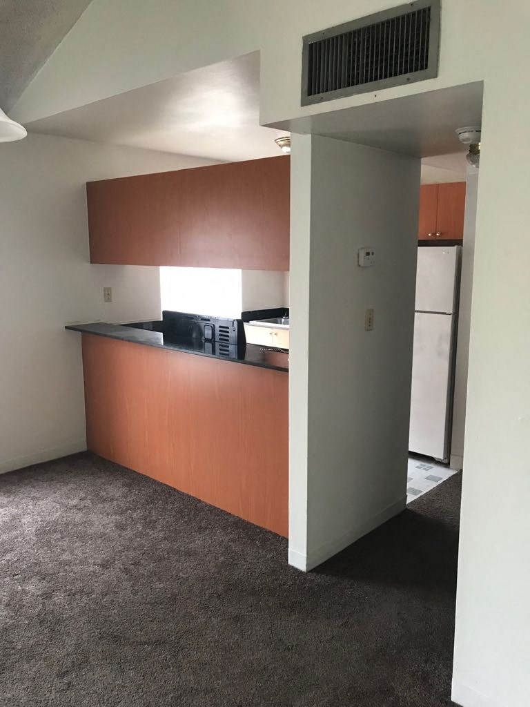 an empty living room with a kitchen in it