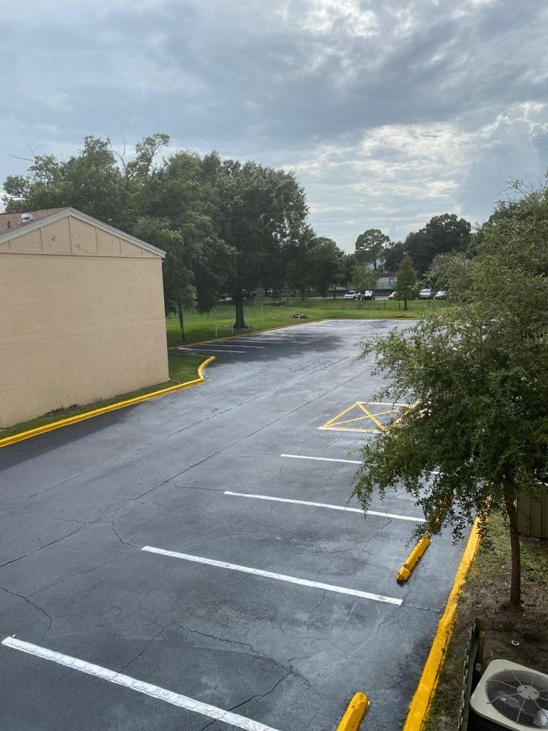 an empty parking lot with trees and a building