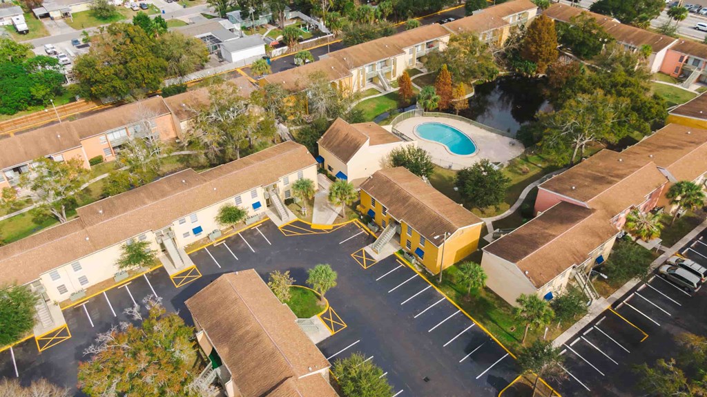 an aerial view of a parking lot with buildings and a pool