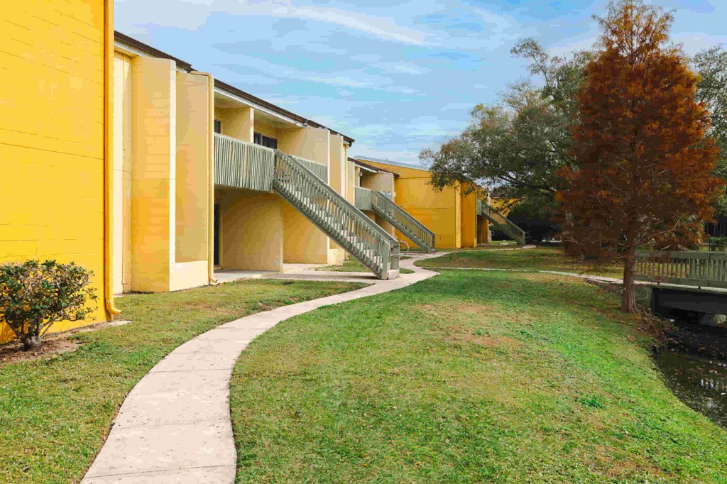a row of yellow buildings with a sidewalk and grass