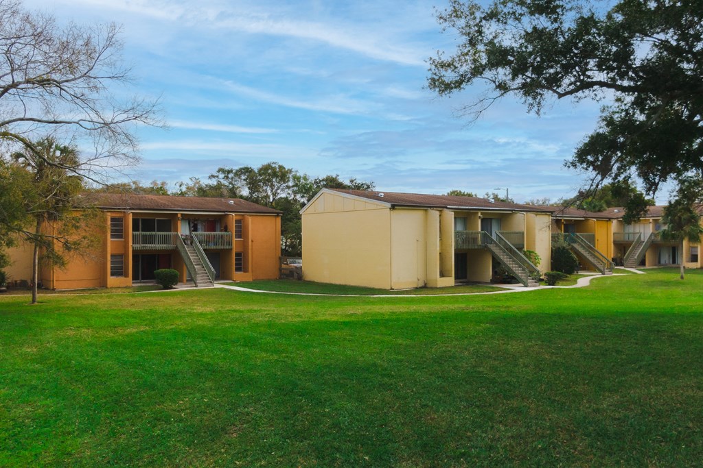 a view of the exterior of an apartment building with a green lawn